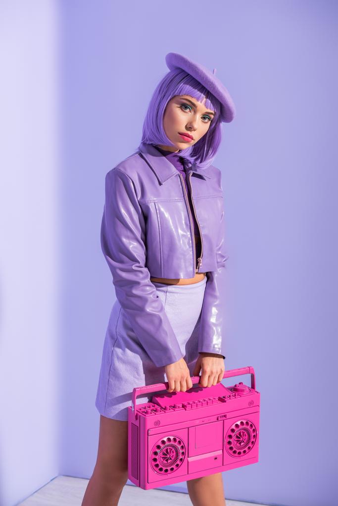 若い女性は人形風のポーズでピンクのレトロテープレコーダーで紫色の背景 - 写真・画像