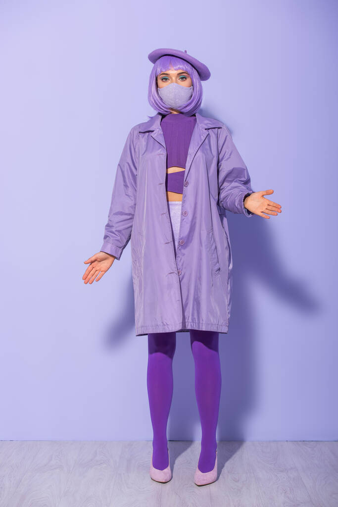 молода жінка, одягнена в ляльковий стиль в медичну маску і берет на фіолетовому барвистому фоні
 - Фото, зображення