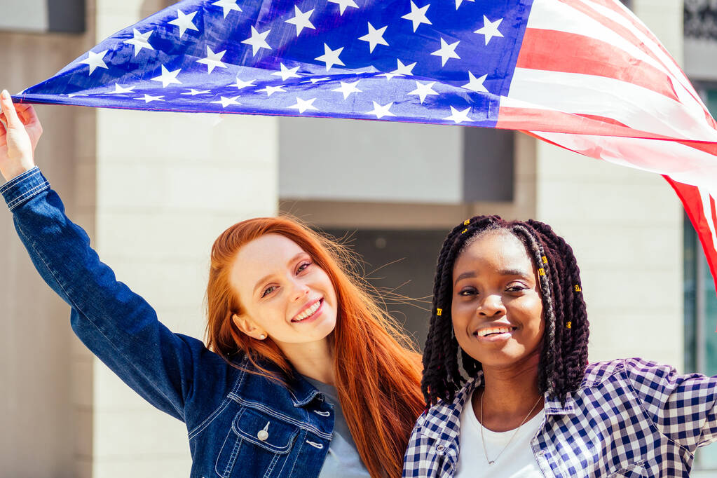 Latynoski i rudowłose rudzielce trzymające flagę USA na ulicy - Zdjęcie, obraz