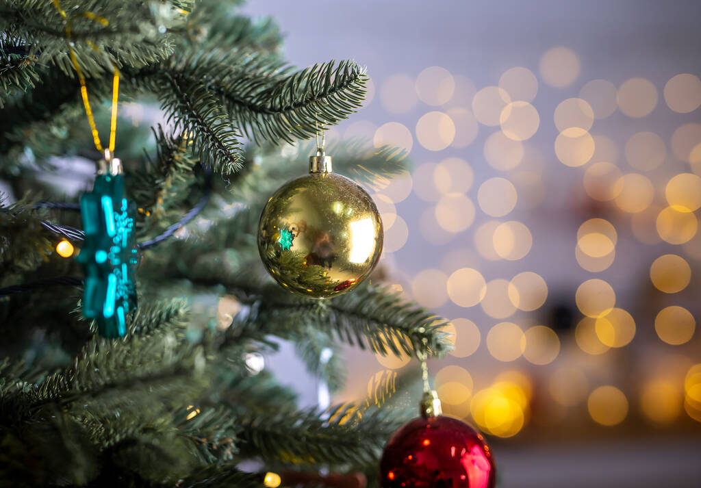 Close up view of beautiful fir branches with shiny golden bauble or ball, xmas ornaments and lights, christmas holidays background. - Foto, Imagen
