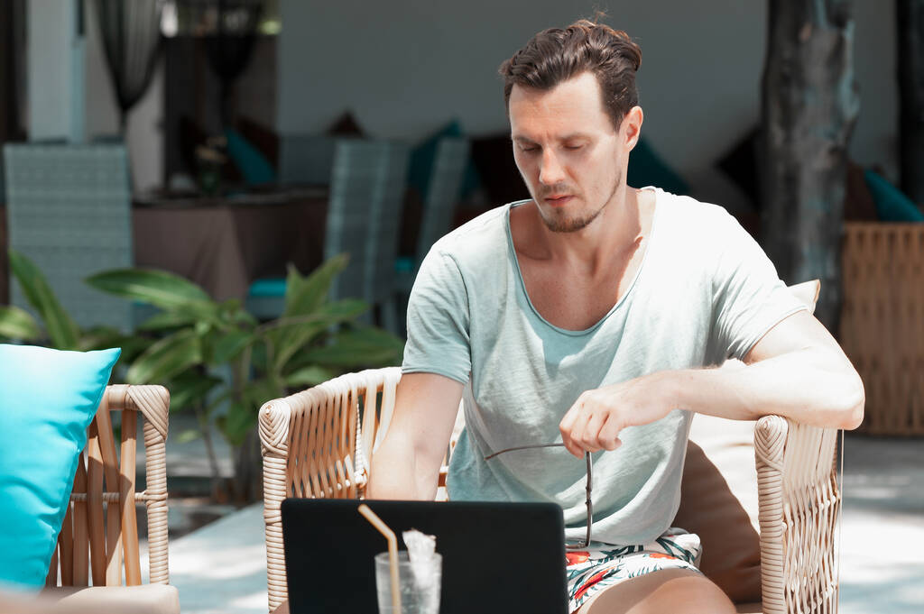 Человек фрилансер работает с ноутбуком на пляже в курорте - Фото, изображение