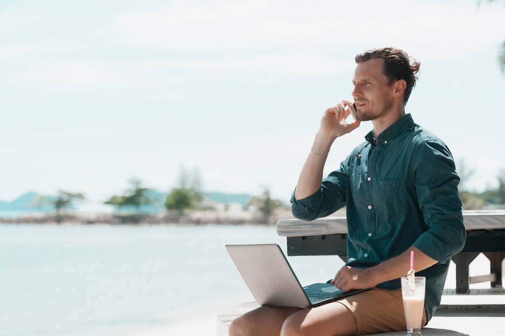 Άνδρας ελεύθερος επαγγελματίας που εργάζεται με φορητό υπολογιστή στην παραλία στο θέρετρο - Φωτογραφία, εικόνα