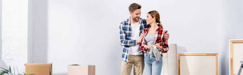 glücklicher junger Mann umarmt Freundin mit Handschuhen zu Hause, Banner - Foto, Bild