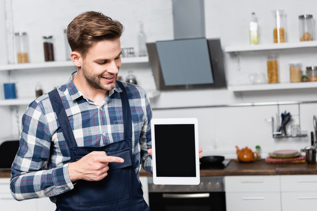 boldog szerelő ujjal mutogató tabletta homályos konyha a háttérben - Fotó, kép