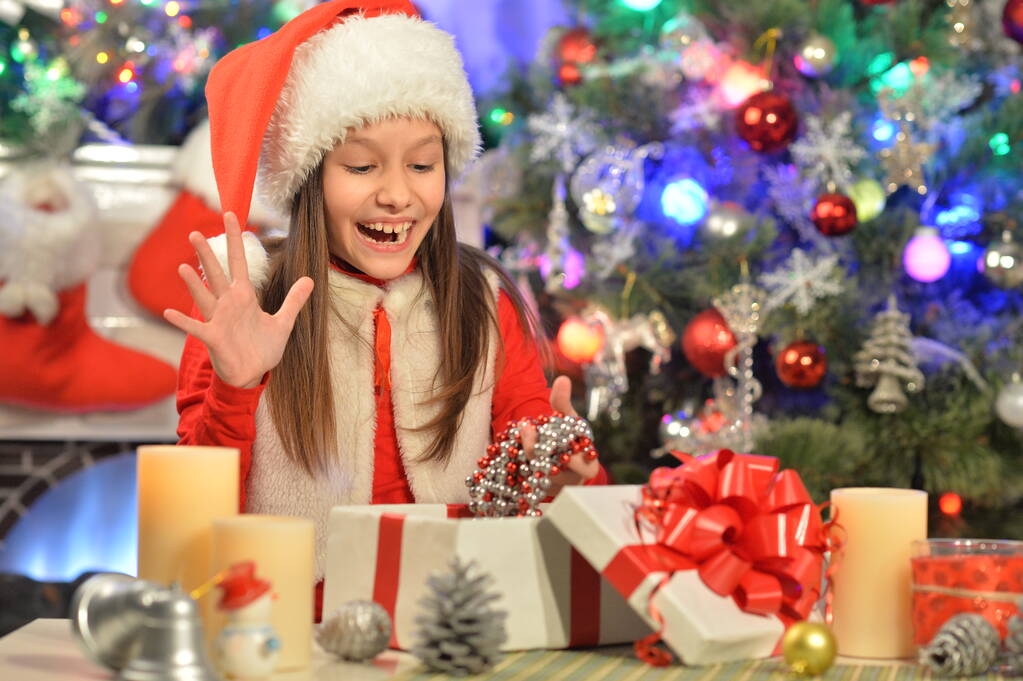 Portrait de fille heureuse dans le chapeau du Père Noël avec cadeau - Photo, image