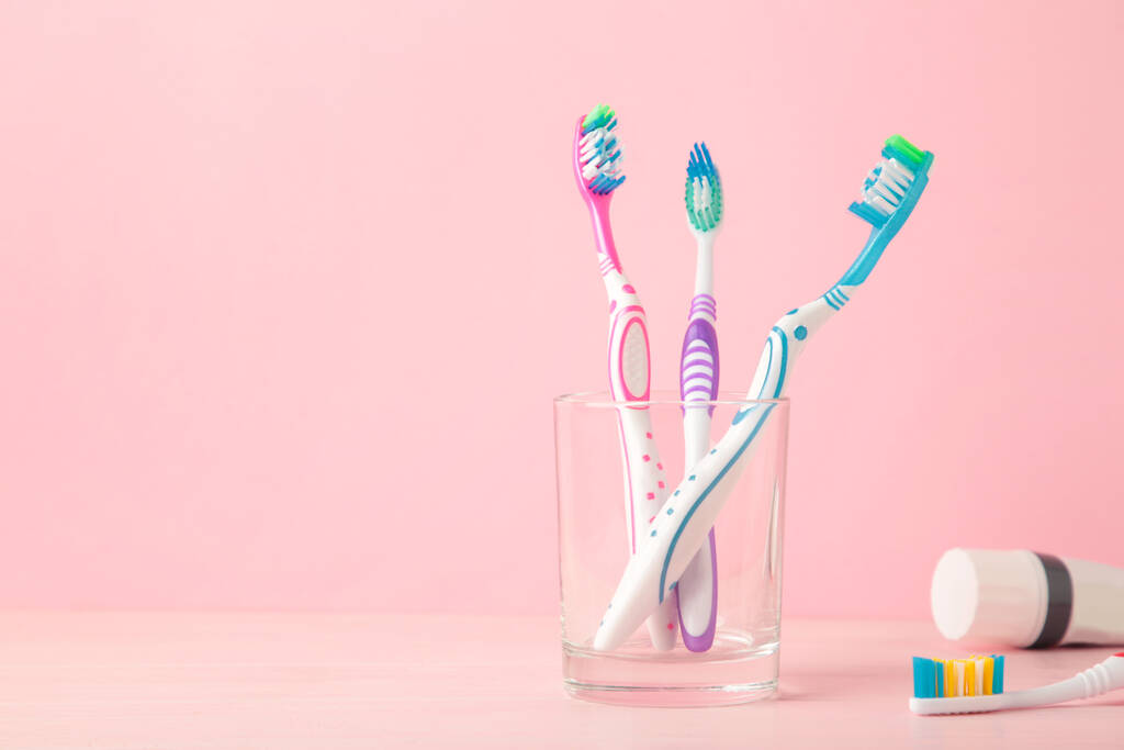 Οδοντόβουρτσες σε γυάλινο σωλήνα με οδοντόπαστα σε ροζ φόντο. Άνω όψη - Φωτογραφία, εικόνα