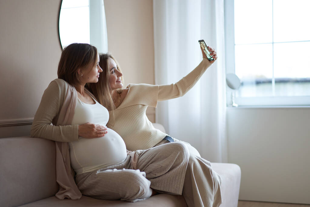 многоэтнические девушки и счастливая беременная женщина делает селфи на смартфоне. Высокое качество фото. - Фото, изображение