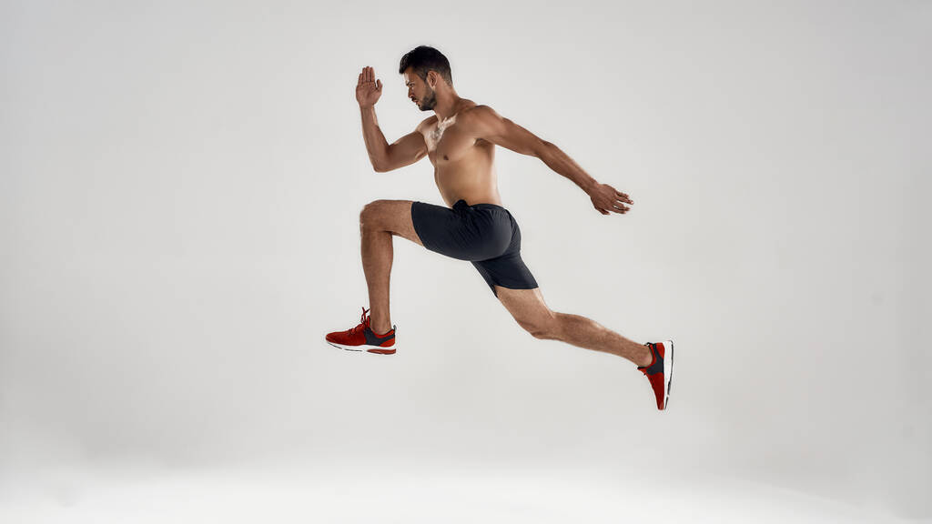 Young handsome caucasian male runner jumping high - Photo, Image