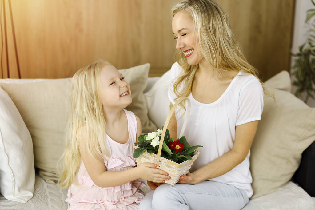 Bonne fête des mères. Enfant fille félicite maman et donne son panier de fleurs de printemps. Concept de famille - Photo, image
