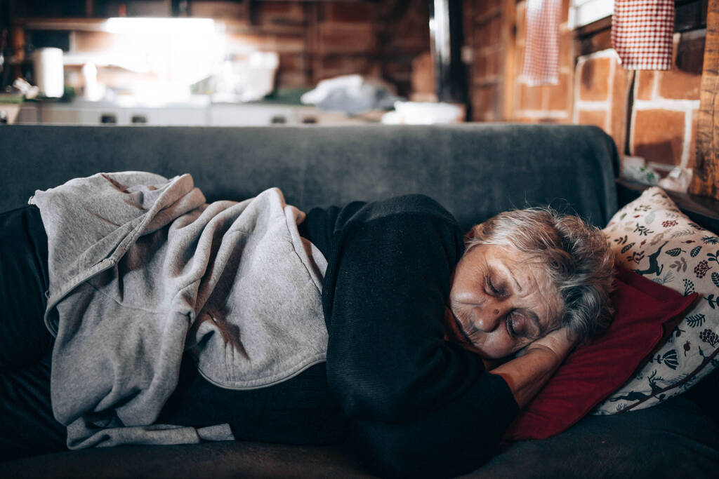 Ältere Frau schläft auf einer Couch im Wohnzimmer - Foto, Bild