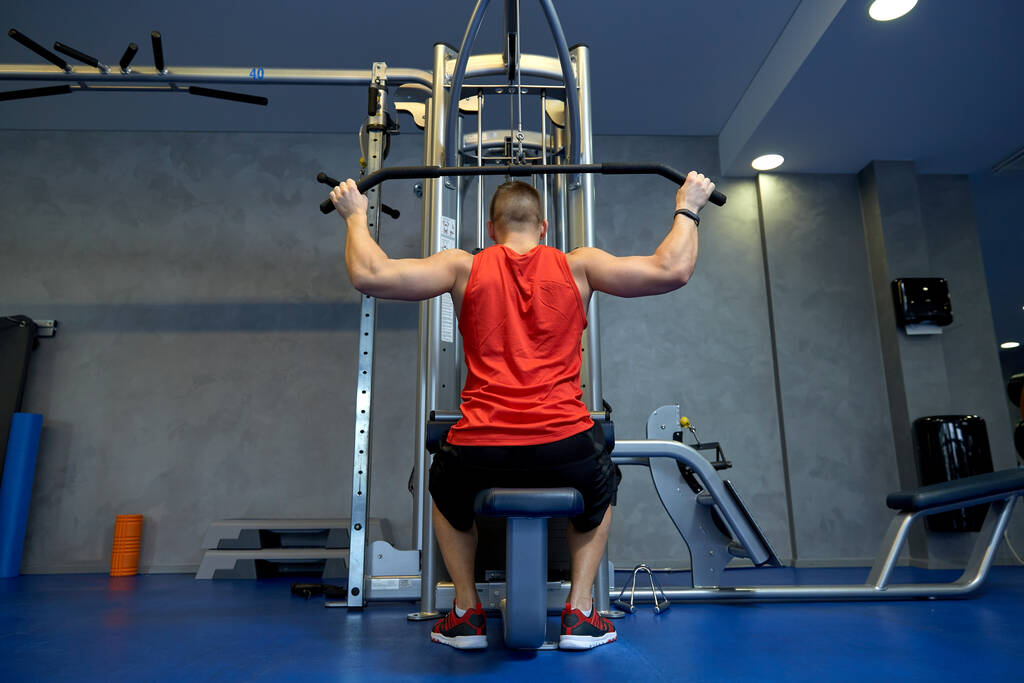 close up of man exercising on cable machine in gym - Photo, Image