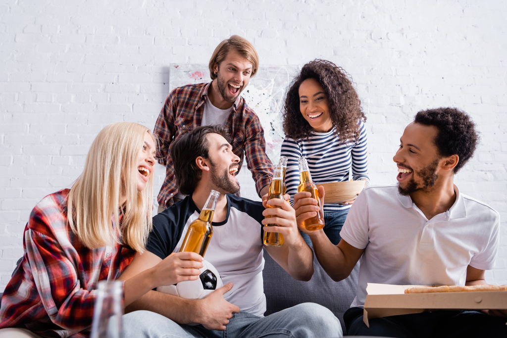 前景にビールとピザを持っている幸せな多民族サッカーファン - 写真・画像