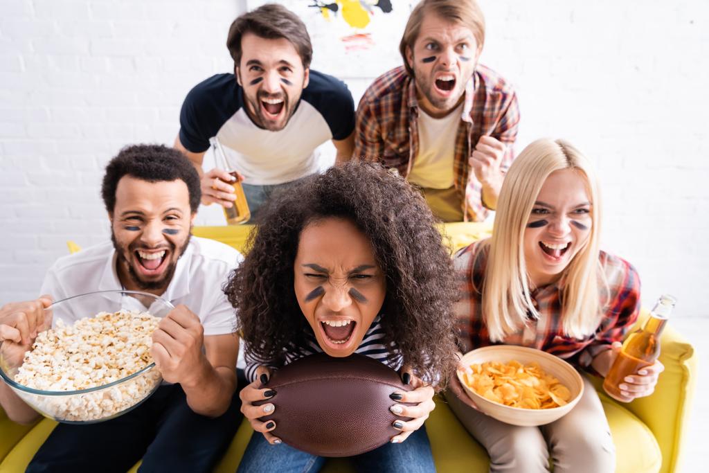 excited multiethnic sports fans with painted faces screaming while watching american football championship  - Photo, Image