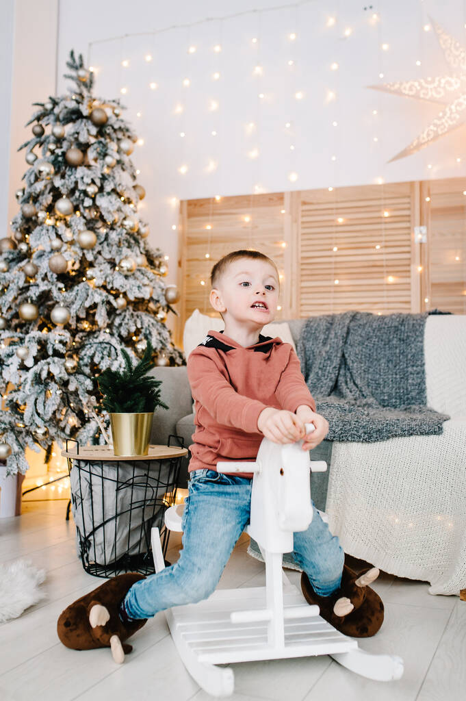 Boy playing near Christmas tree. Happy New Year and Merry Christmas. Christmas decorated interior. The concept of family holiday. - Photo, Image