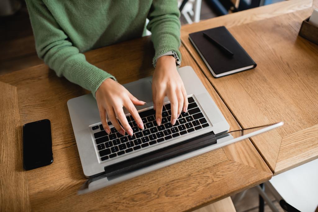 обрізаний вид афроамериканської жінки, що друкує на клавіатурі ноутбука в кафе
 - Фото, зображення