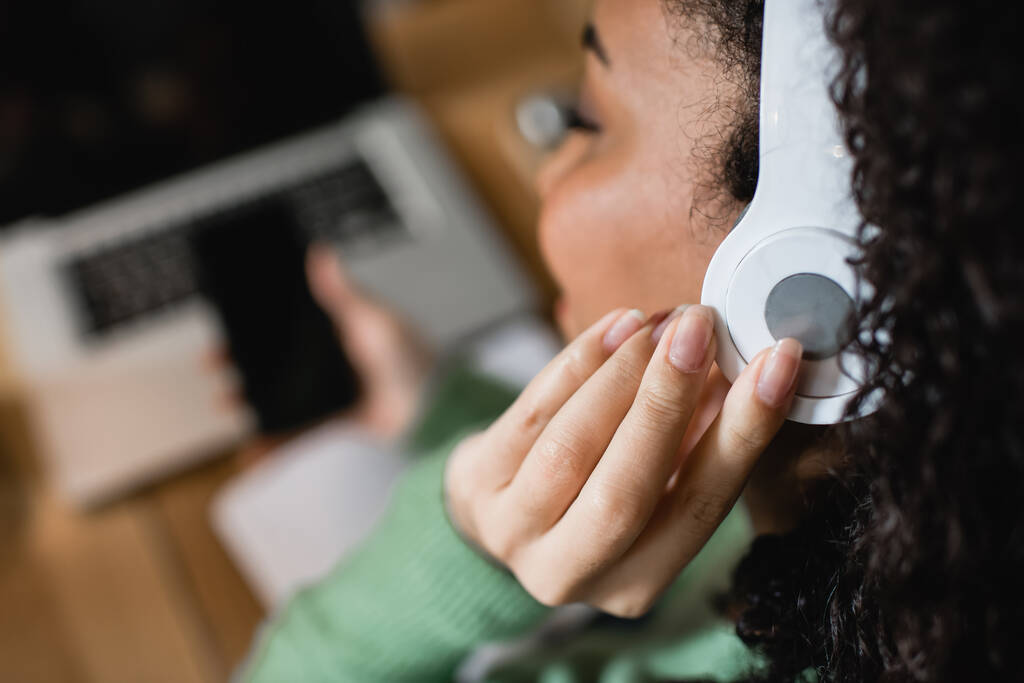 mujer afroamericana escuchando podcast y tocando auriculares  - Foto, Imagen