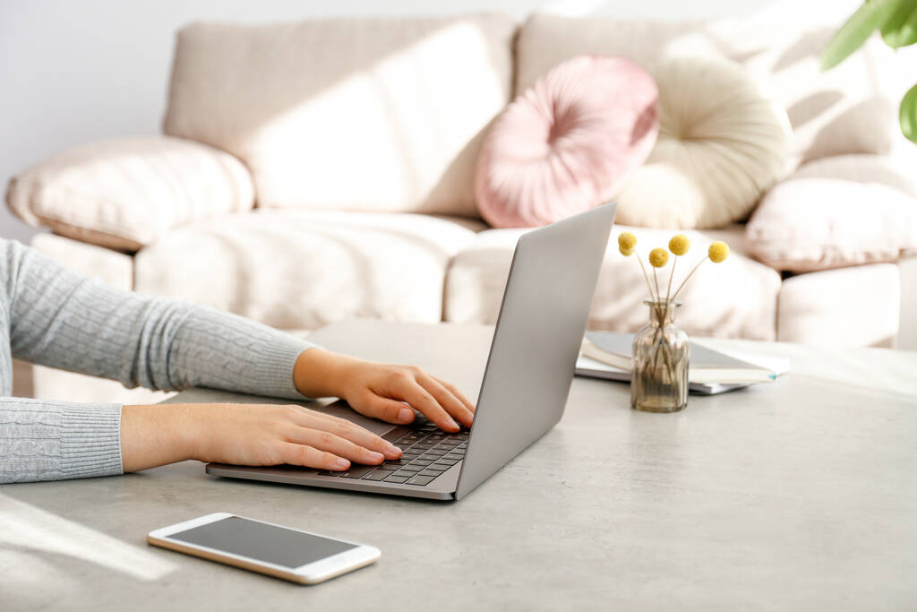 Werk vanuit huis concept. Gehakt van vrouwenhanden die typen op een laptop. Vrouwelijke freelancer werkt in haar woonkamer. Close up, kopieer ruimte voor tekst. - Foto, afbeelding