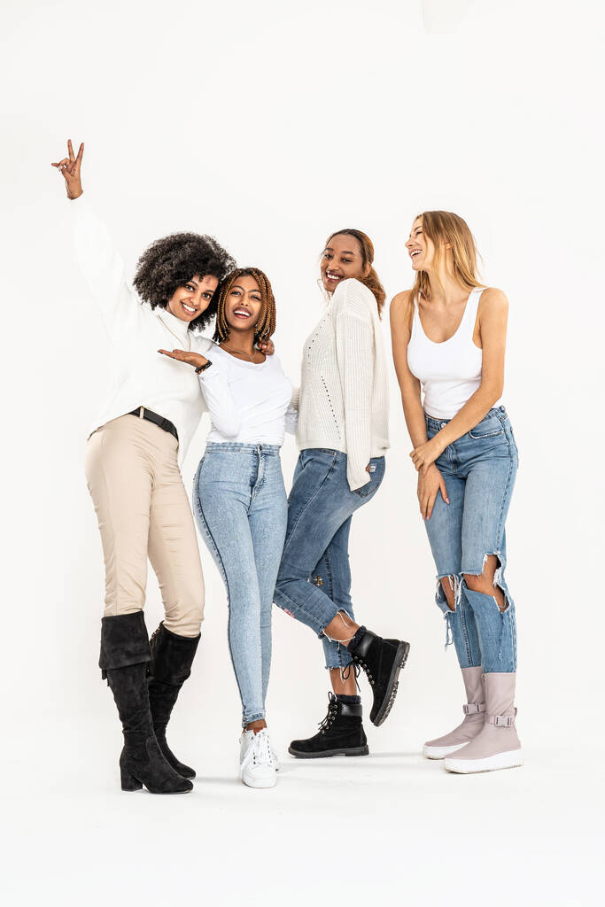 Gruppe junger multiethnischer attraktiver Mädchen, die zusammen lächeln und Spaß haben und im Studio auf weißem Hintergrund posieren. Freundschaft und echte Emotionen. - Foto, Bild