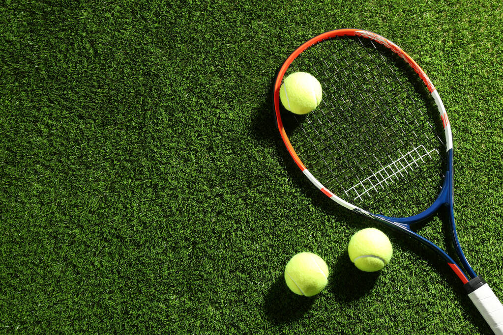 Ρακέτα του τένις και μπάλες στο πράσινο γρασίδι, επίπεδη lay. Χώρος για κείμενο - Φωτογραφία, εικόνα