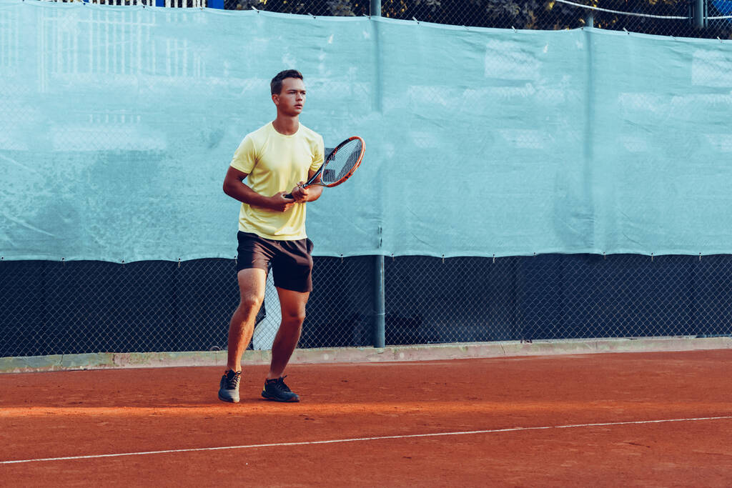 Młody przystojny mężczyzna gra w tenisa na korcie tenisowym - Zdjęcie, obraz