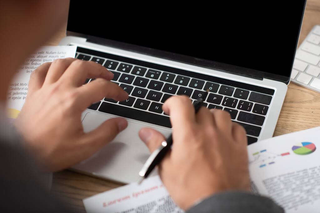 visão parcial do comerciante digitando no laptop no local de trabalho, foreground turvo - Foto, Imagem