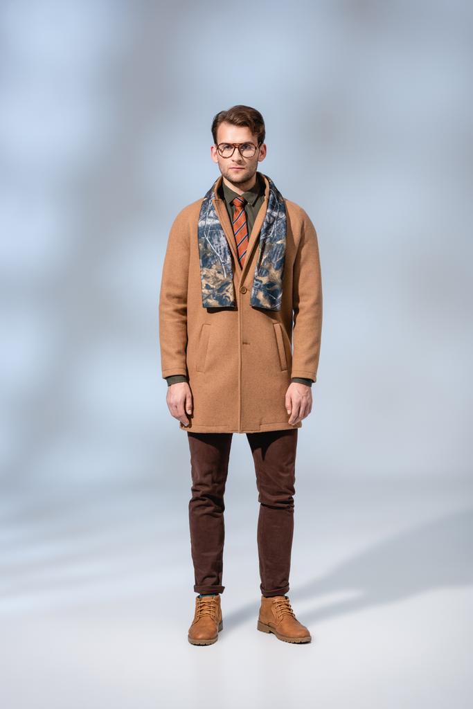スタイリッシュな男の完全な長さで冬のコートは灰色のブーツに立って - 写真・画像