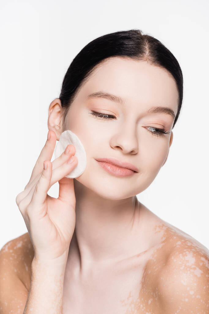 νεαρή όμορφη γυναίκα με λεύκη καθαρισμού πρόσωπο με βαμβάκι pad απομονώνονται σε λευκό - Φωτογραφία, εικόνα