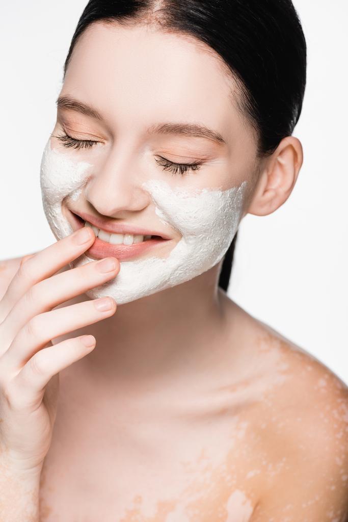 sourire jeune belle femme avec vitiligo et masque d'argile sur le visage isolé sur blanc - Photo, image