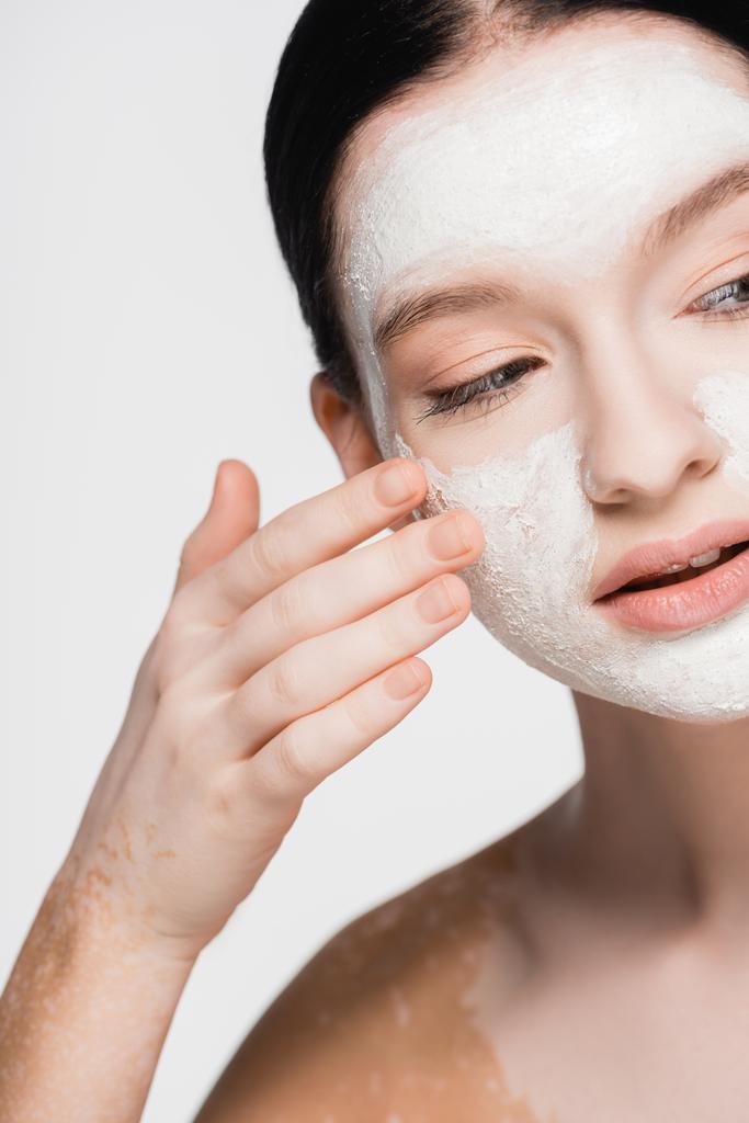 fiatal gyönyörű nő vitiligo és agyag maszk az arcon elszigetelt fehér - Fotó, kép