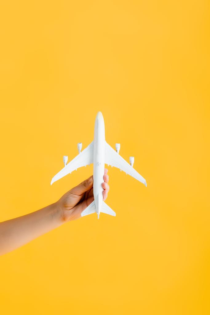 καλλιεργούμενη άποψη της γυναίκας που κρατά το παιχνίδι αεροπλάνο απομονωμένο σε κίτρινο  - Φωτογραφία, εικόνα