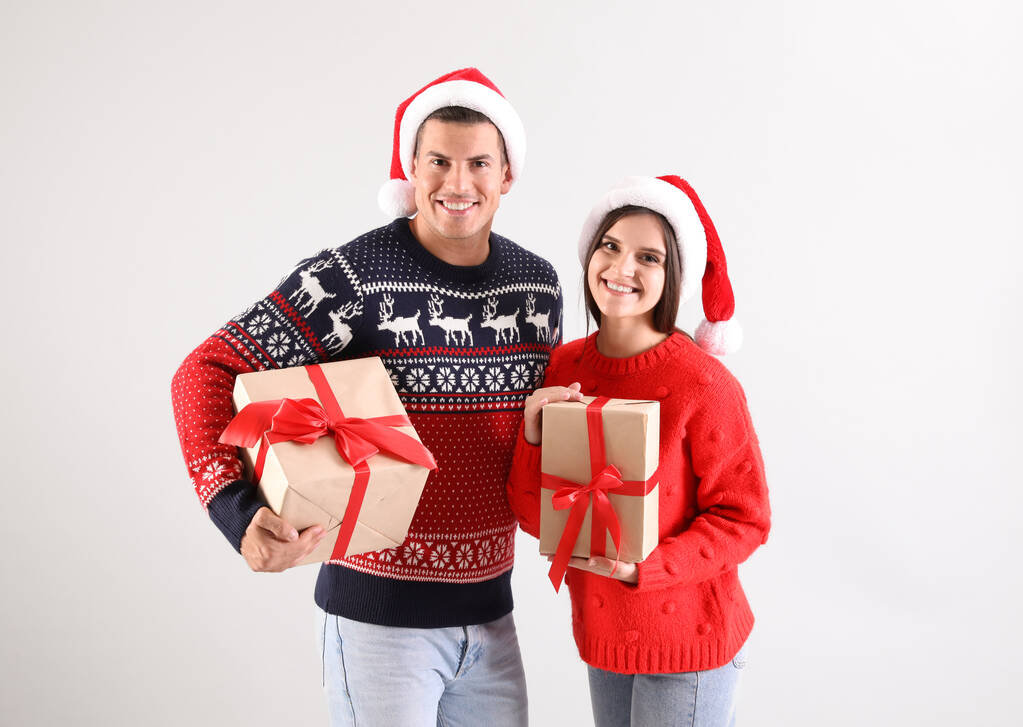 美しいです幸せなカップルでサンタ帽子保持クリスマスギフト上の光の背景 - 写真・画像