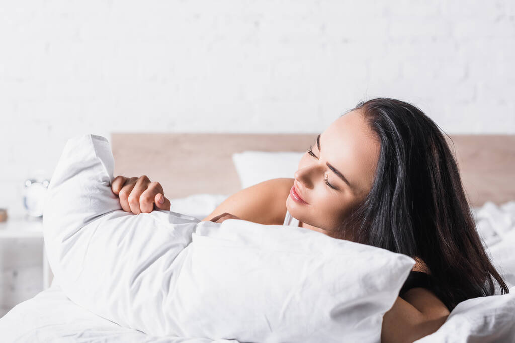 jovem morena mulher na cama com travesseiro - Foto, Imagem