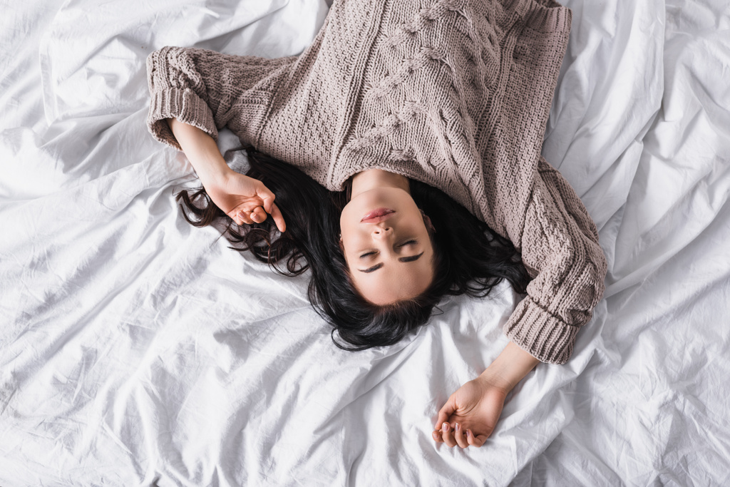 トップビューの若いブルネットの女性のセーターで寝る朝 - 写真・画像