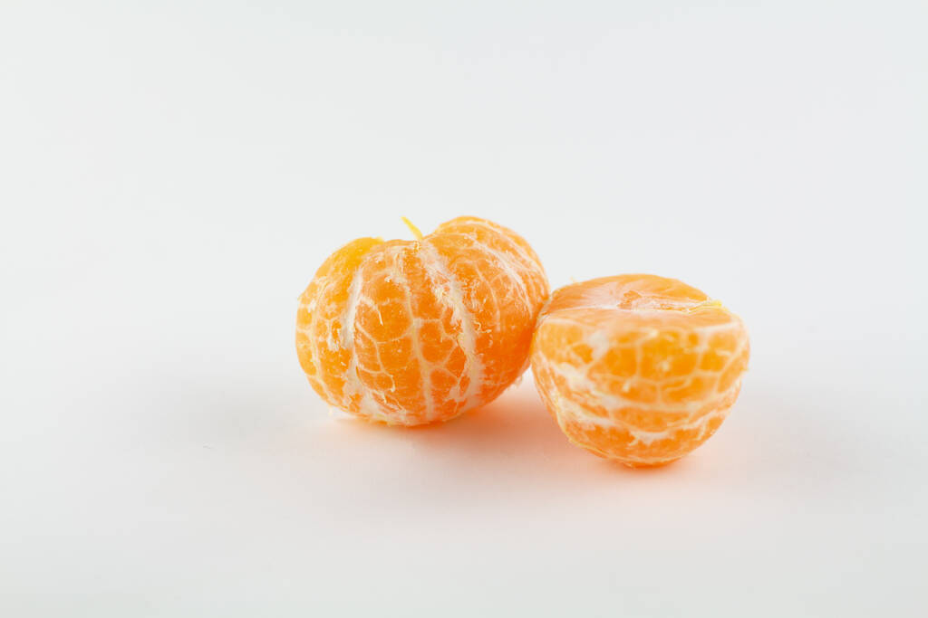 een mooie rijpe geschilde mandarijn op een witte achtergrond - Foto, afbeelding