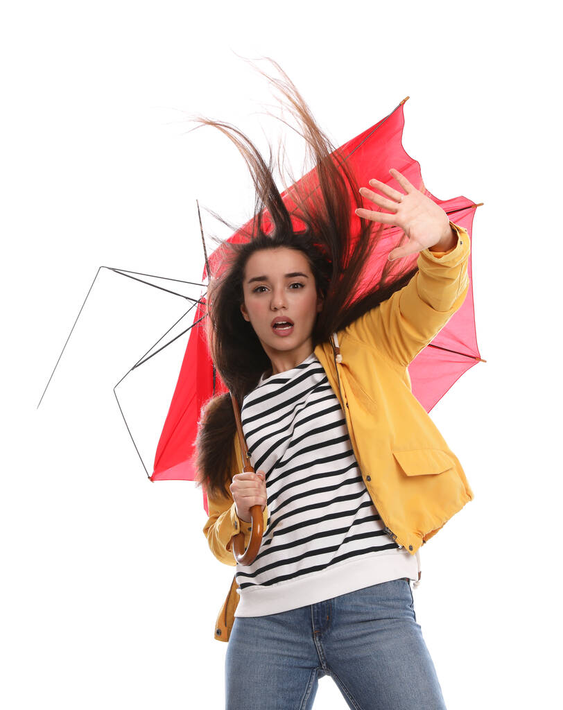Mujer emocional con paraguas atrapado en ráfaga de viento sobre fondo blanco - Foto, imagen