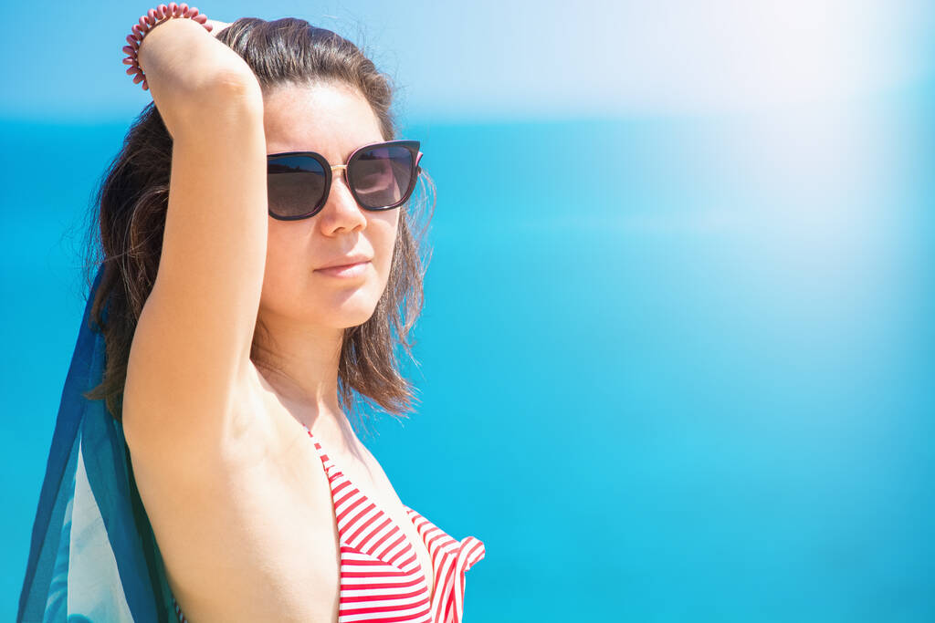 Όμορφο κορίτσι με μαντήλι ηλιοθεραπεία στην παραλία - Φωτογραφία, εικόνα