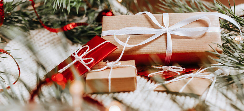 Πρωτοχρονιάτικα δώρα σε πλεκτό φόντο με χριστουγεννιάτικο δέντρο και παιχνίδια στα φώτα - Φωτογραφία, εικόνα