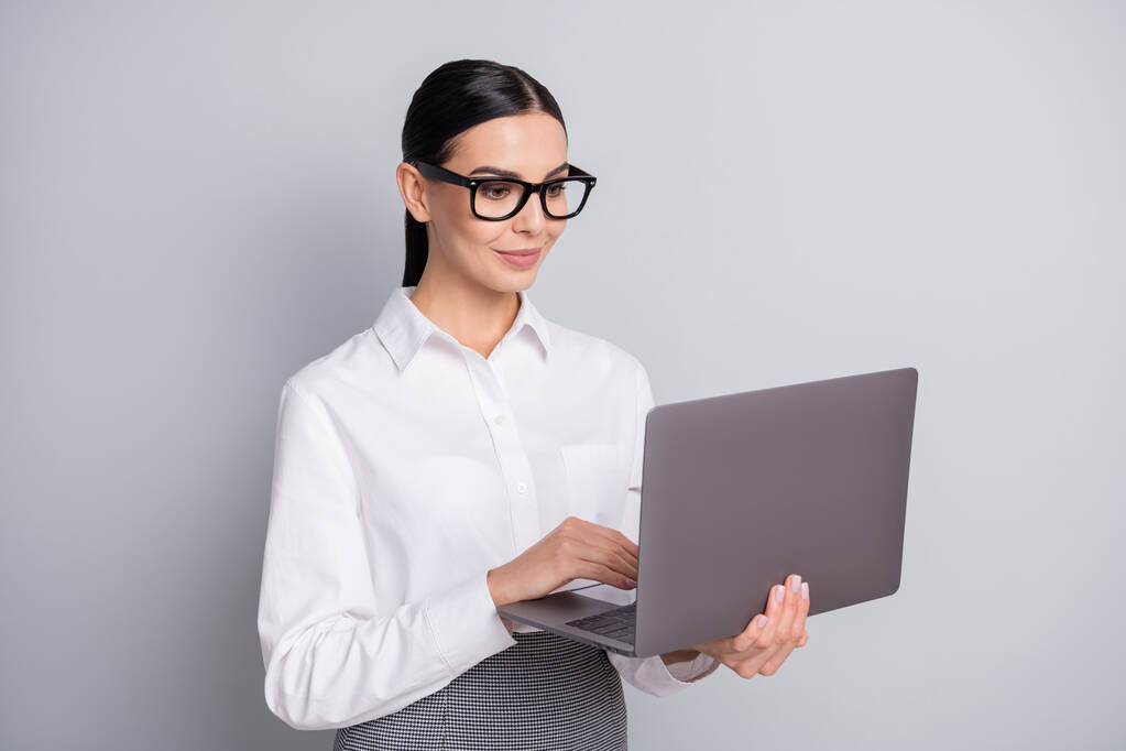Fénykép a nyugodt programozó lány hold laptop megjelenés képernyő kopás szemüveg fehér ing elszigetelt szürke szín háttér - Fotó, kép