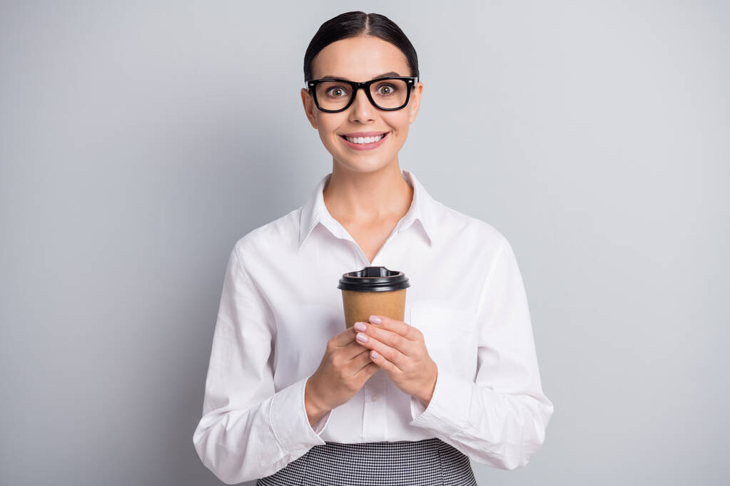 Kuva nuori innoissaan nainen pidä kuppi kahvia näyttää kamera kiiltävä hymy kulumista silmälasit valkoinen paita eristetty harmaa väri tausta - Valokuva, kuva