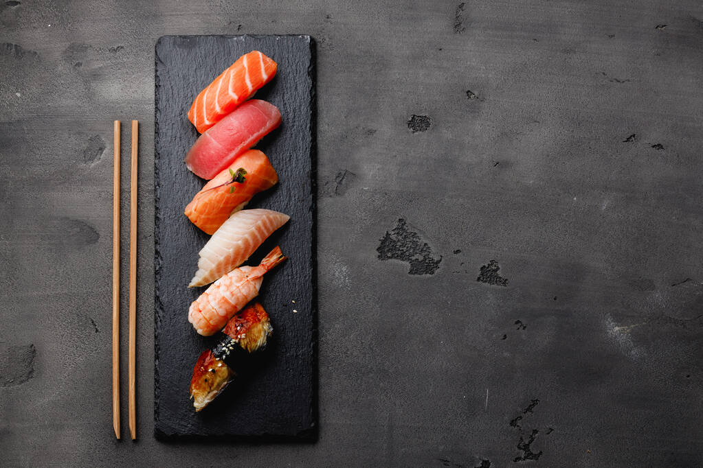 Joukko nigiri sushi tarjoillaan lautasella harmaalla pohjalla - Valokuva, kuva