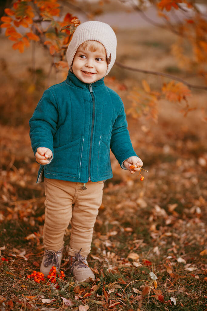 Het gelukkige kind komt eraan. Een jongen gekleed in een groen jasje en bruine broek. - Foto, afbeelding