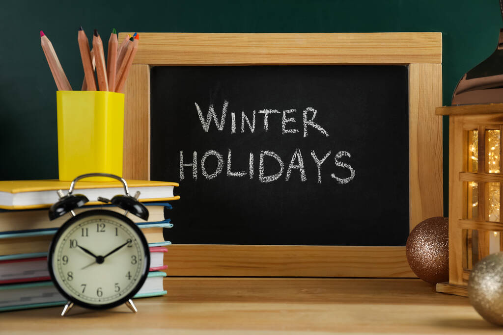 Chalkboard με κείμενο Χειμερινές διακοπές και σχολικά είδη σε ξύλινο τραπέζι - Φωτογραφία, εικόνα