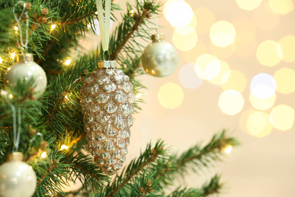 Cone vormige vakantie bauble opknoping aan kerstboom tegen wazig licht, close-up. Ruimte voor tekst - Foto, afbeelding