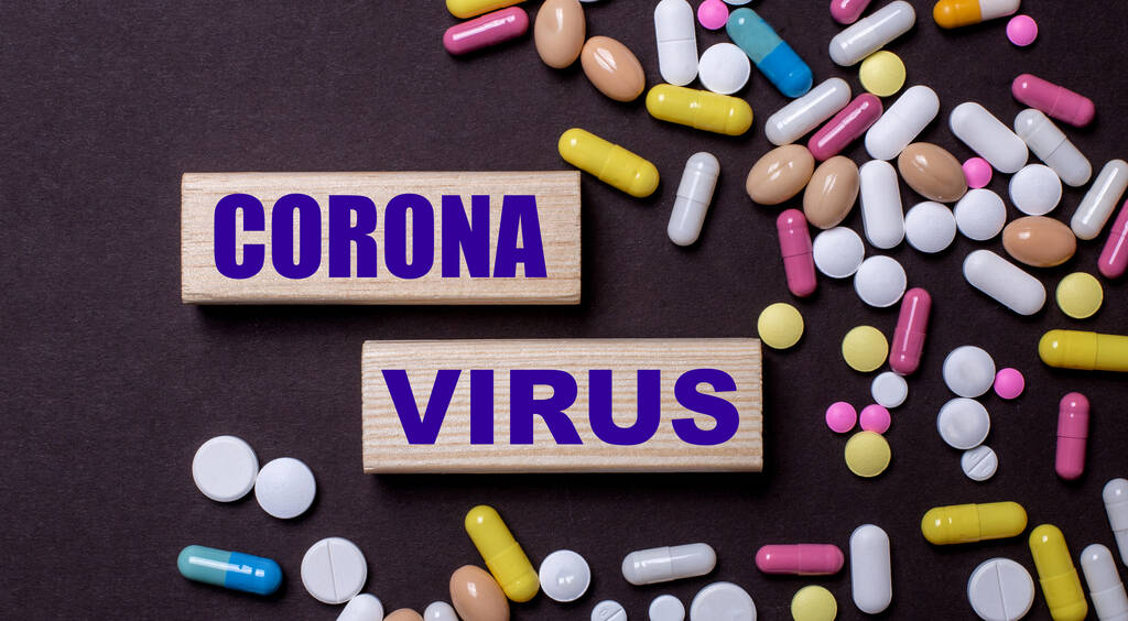 CORONA VIRUS est écrit sur des blocs de bois près de pilules multicolores. Concept médical - Photo, image