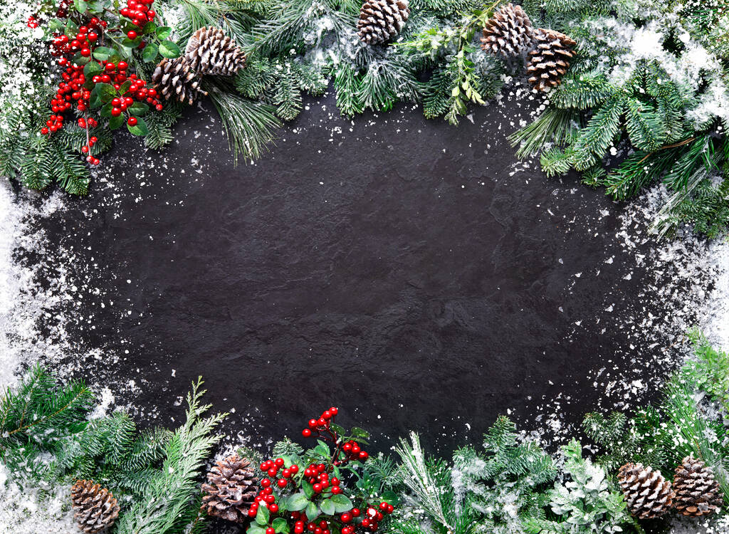 Noël et Nouvel An fond avec branches de sapin, houx et chutes de neige sur une planche de pierre sombre - Photo, image