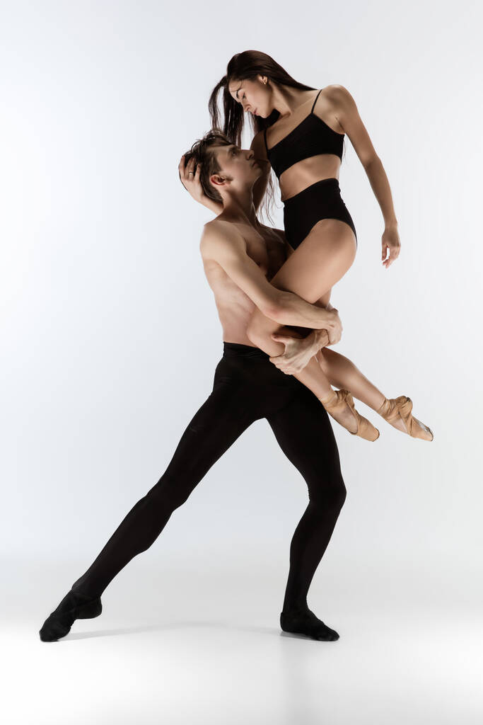 Νέοι και χαριτωμένοι χορευτές μπαλέτου σε minimal μαύρο στυλ απομονωμένοι σε λευκό φόντο στούντιο - Φωτογραφία, εικόνα
