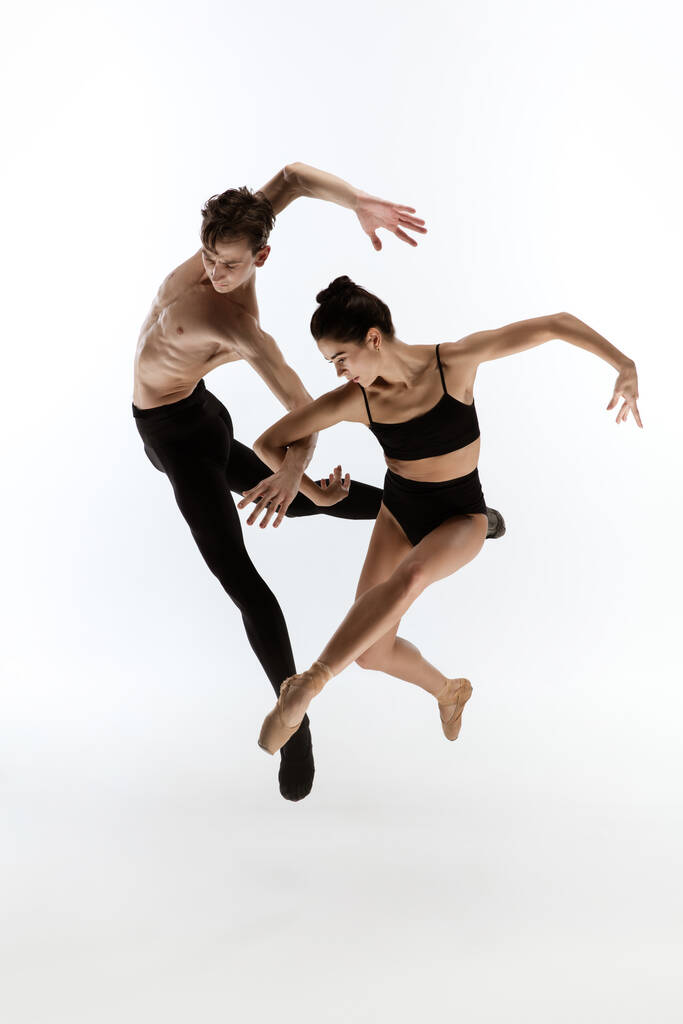 Молоді та витончені танцюристи балету в мінімальному чорному стилі ізольовані на білому фоні студії
 - Фото, зображення