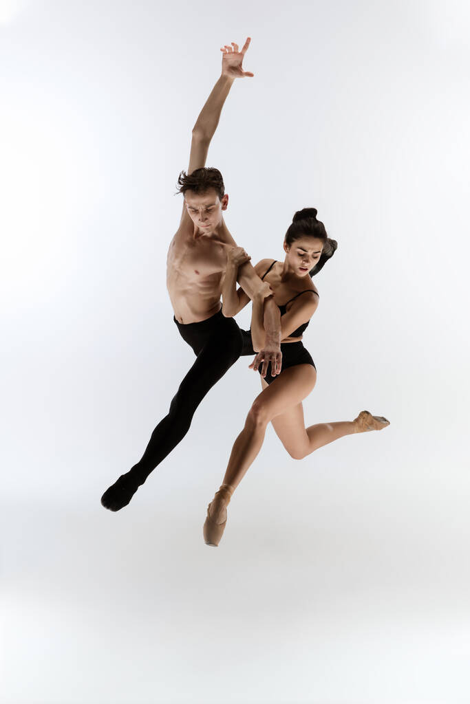 Dois dançarinos de balé graciosos homem e mulher em estilo preto mínimo dançando isolado no fundo do estúdio branco - Foto, Imagem