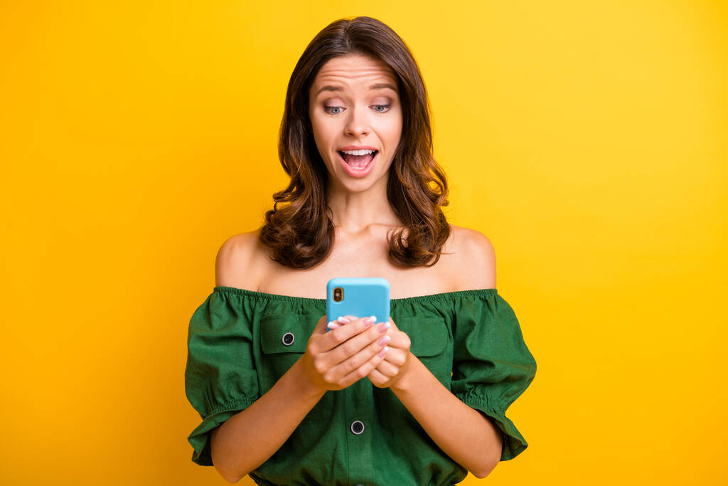 Fotografie okouzlující mladá krásná dáma držet smartphone ohromený zpráva izolované na žlutém pozadí barvy - Fotografie, Obrázek