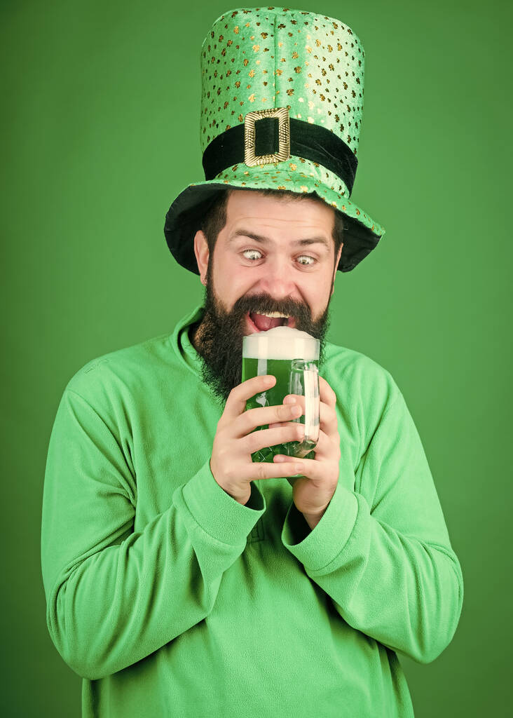 Napoje alkoholowe. Zacznijmy imprezę Patricków. Irlandzka tradycja. Brutalny, brodaty hipster pije piwo. Irlandzki pub. Picie części z piwem. Święto i menu świąteczne. Barwione zielone tradycyjne piwo - Zdjęcie, obraz